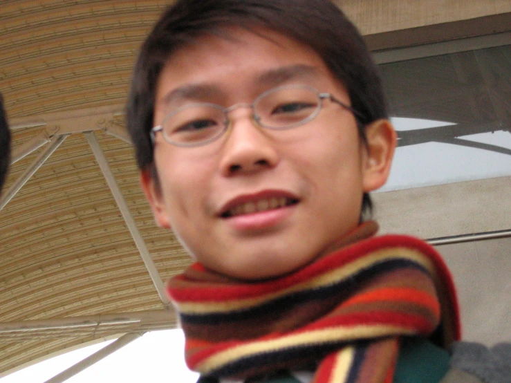 an asian male in glasses has an umbrella over his head