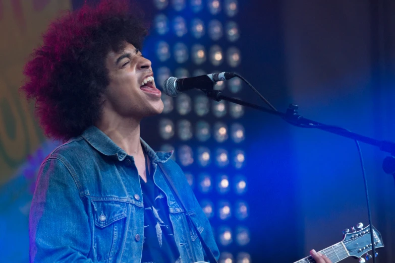 a man singing into a microphone and holding a guitar