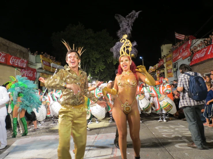 two performers dressed as elvis presley and mardi gras, walk down the street