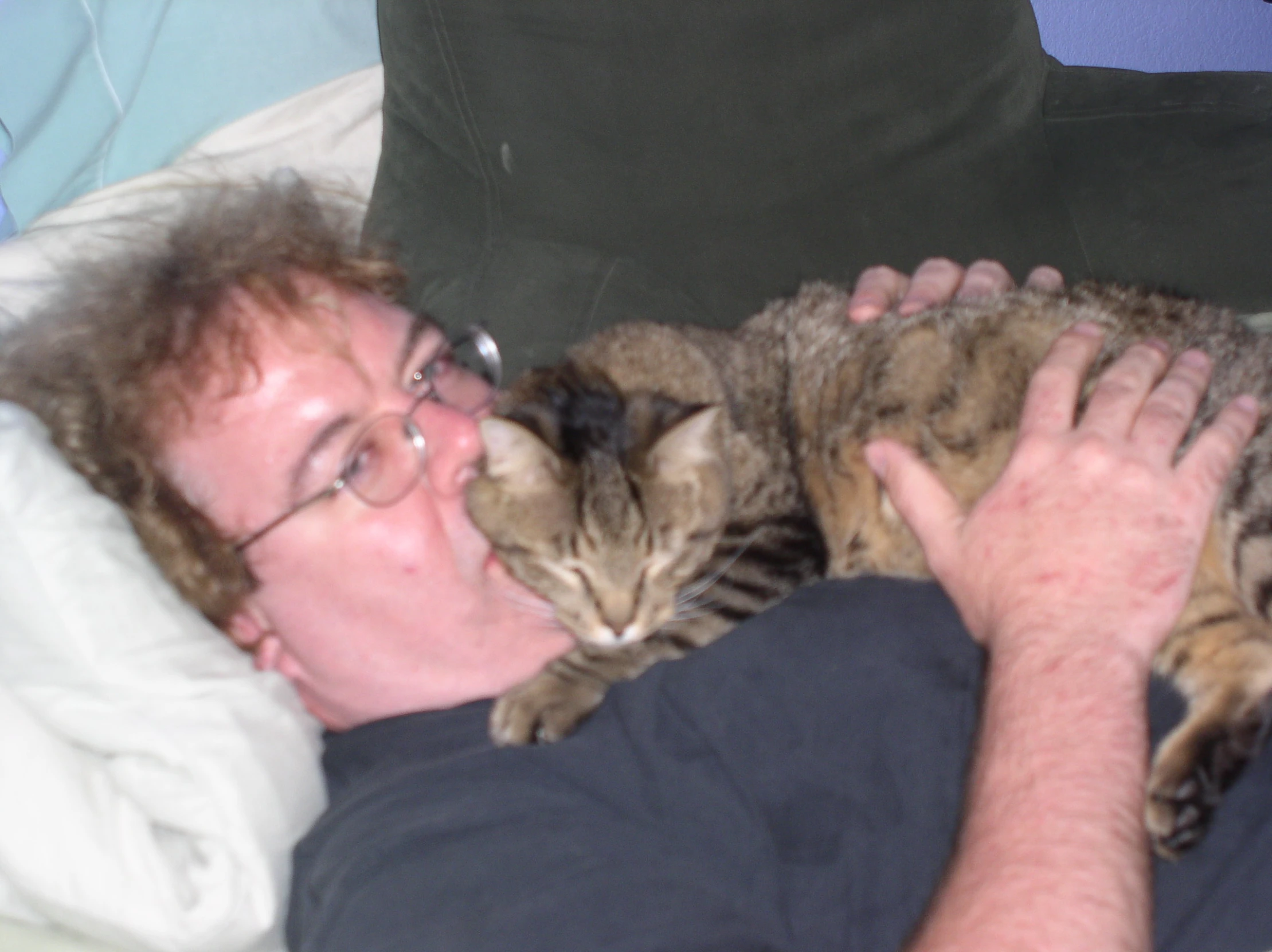 the man is snuggled up in bed with his cat