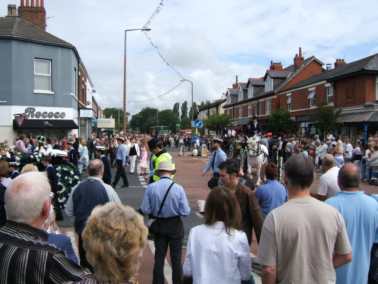 people crowding in the street with many buildings