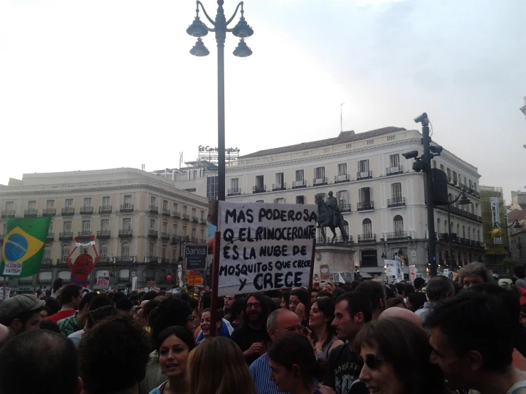 a large group of people on the street with a sign in the middle