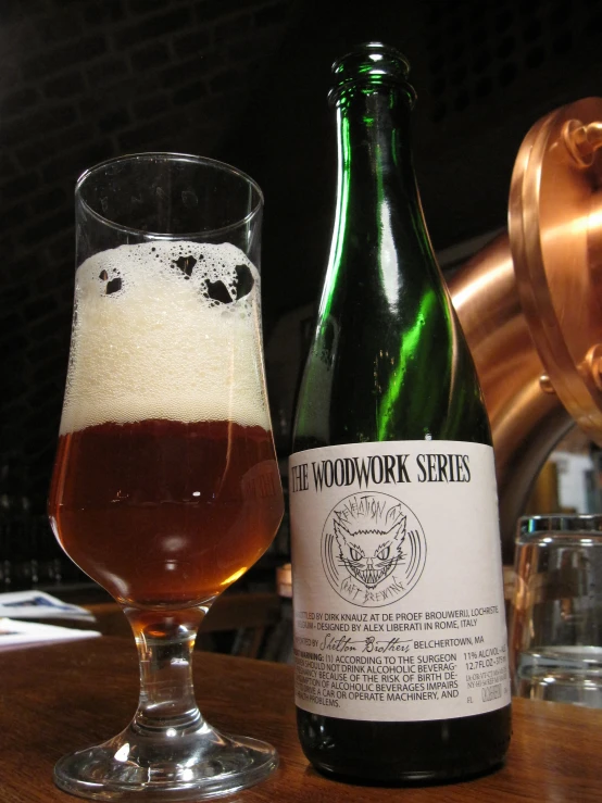 a glass with some beer next to a bottle on a table