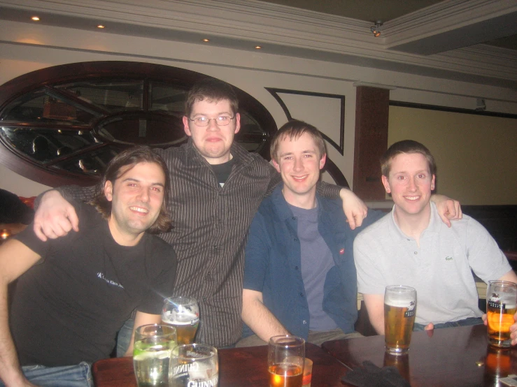 group of men sitting at a table with beer glasses