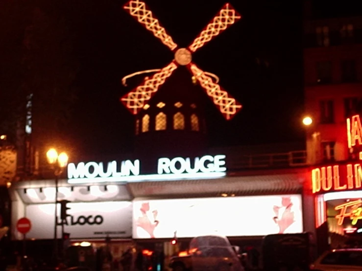 a neon sign in front of a building with a lighted windmill