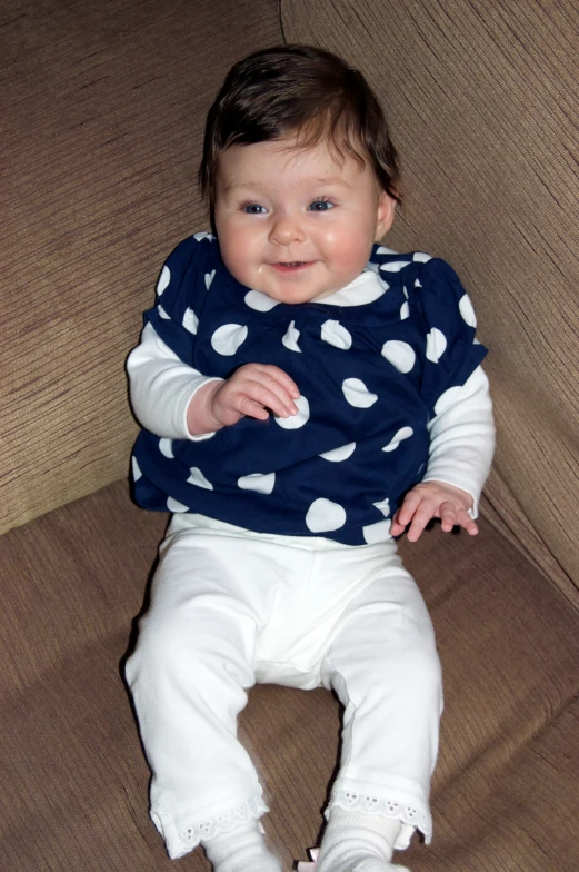 a smiling baby wearing polka dot shirt and pants