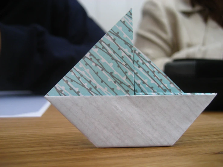 a white origami boat on a wooden table