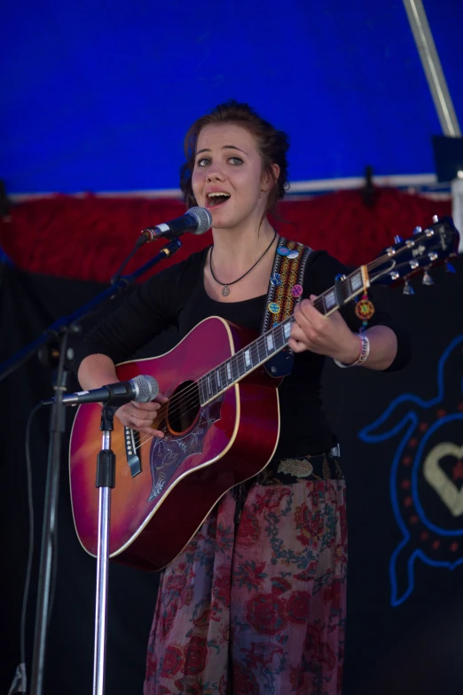 a woman standing at a microphone singing into a microphone