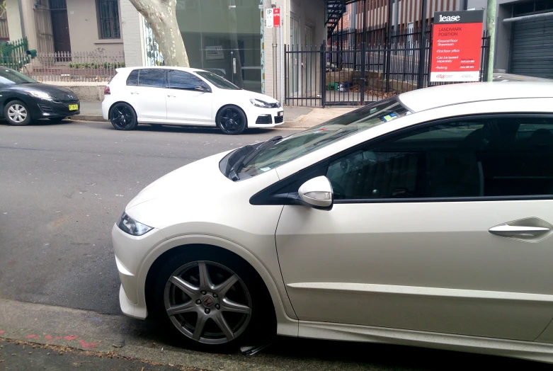 two white cars are parked on the side of a street