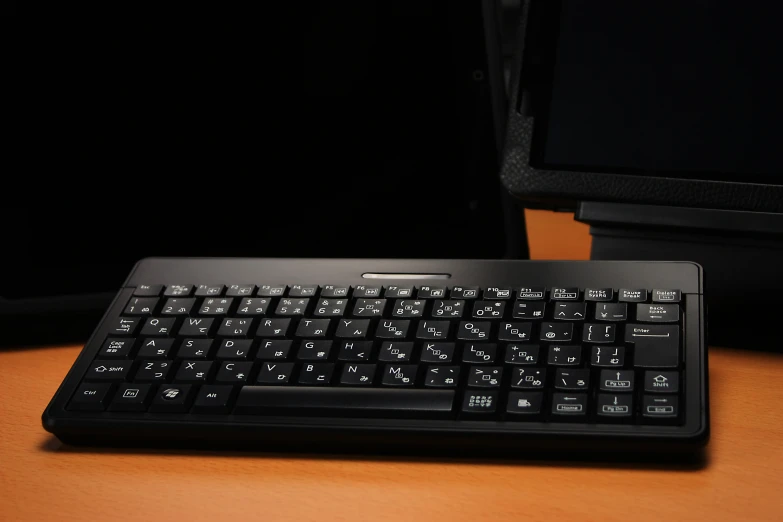 a keyboard on a desk next to another laptop