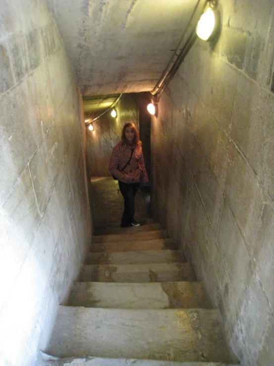 a woman walking up the stairs in a dark tunnel
