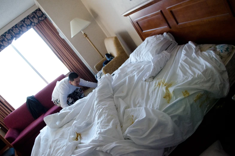 a person sits on a bed covered in white sheets