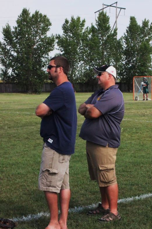 two men in the grass are talking and holding hands