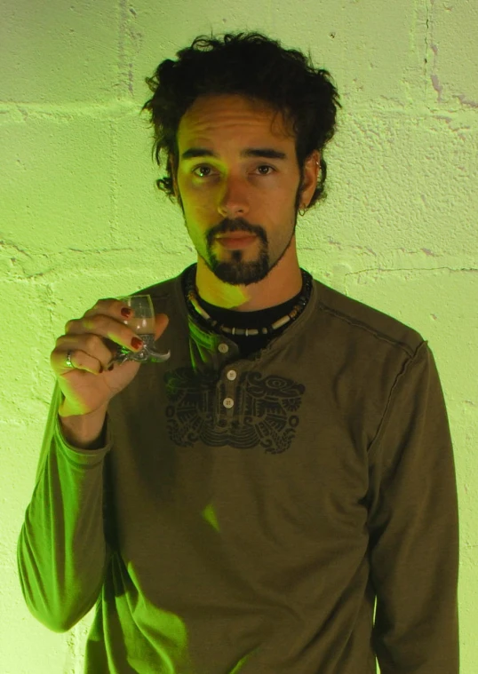 a man is drinking wine with a green glow on the wall