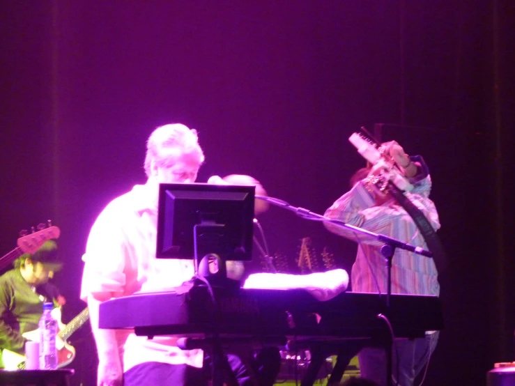 a band playing musical instruments in front of purple lights