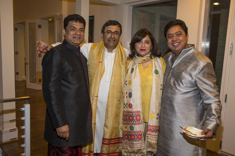 a man poses with other people, while one holds a plate of food