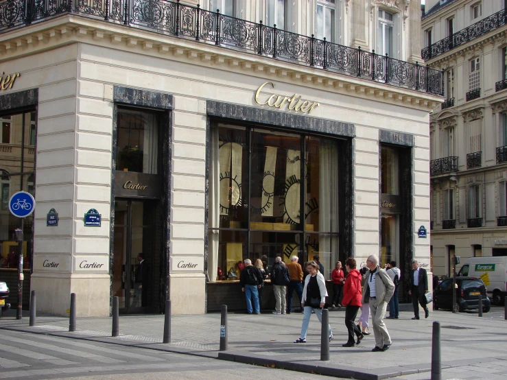 people walk on the sidewalk outside of a store