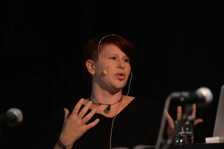 a woman with a pair of earbuds in her mouth speaking into a microphone