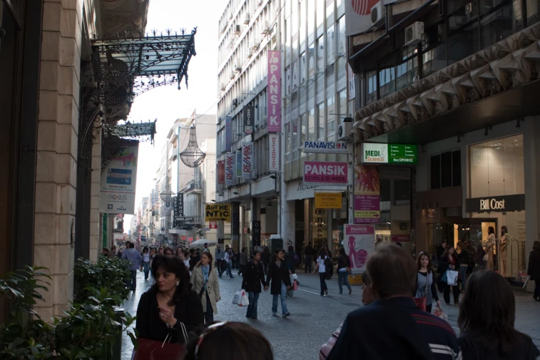 several people walking on a city street near tall buildings