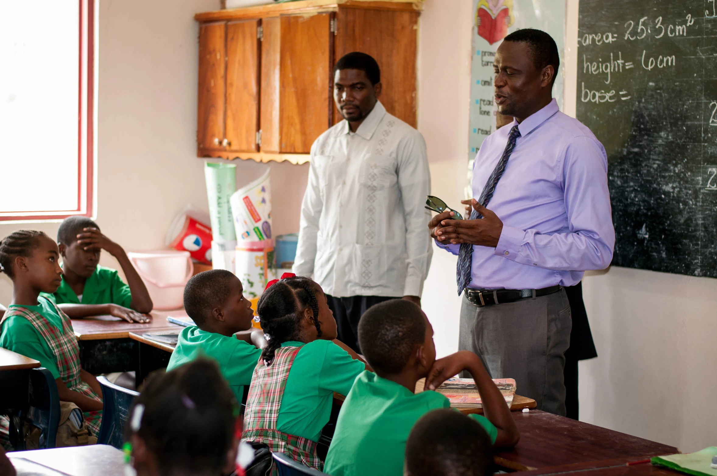 two men in white shirts standing next to students