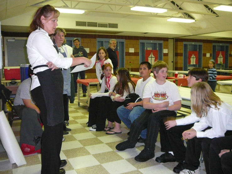 two females in uniforms are standing on the checkered floor while some people watch