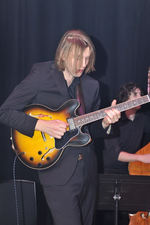 a man in suit playing guitar on stage