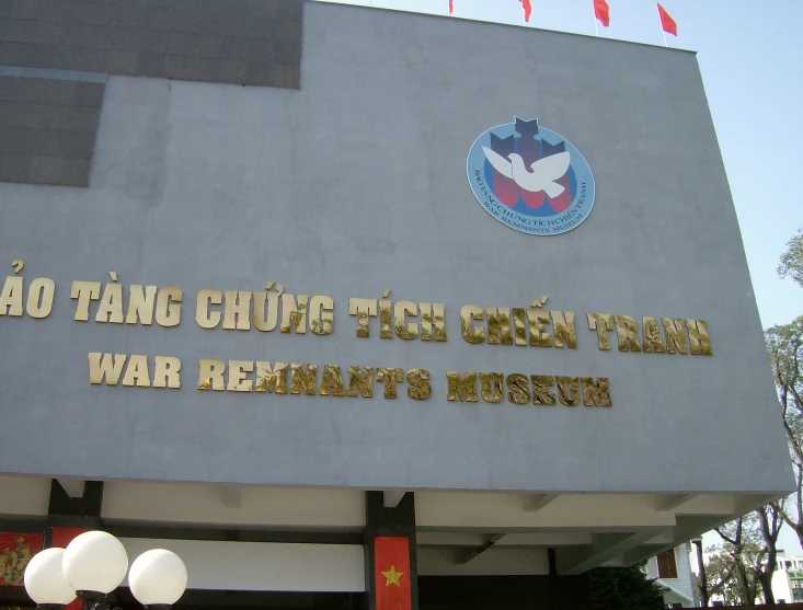 a building has several gold letters that read vietnamese and two red flags hanging on it