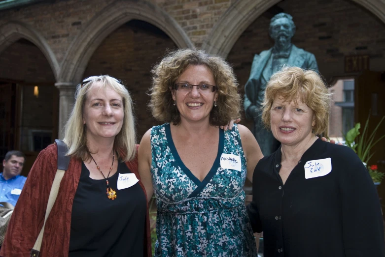 three women are posing for a picture in front of a statue