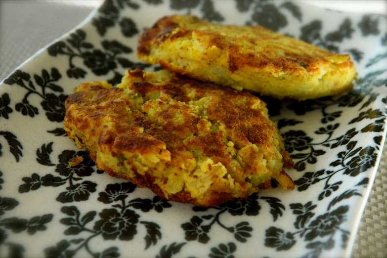 two crab cakes sitting on a plate on top of a table