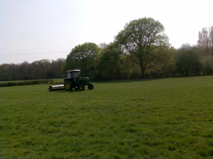 a farmer operating a tractor on a large, grassy field