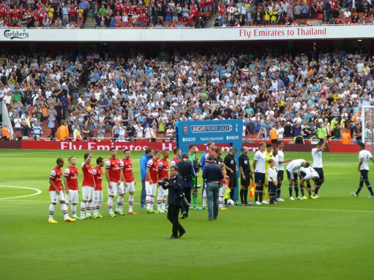 a group of soccer players are on the field while fans stand and watch