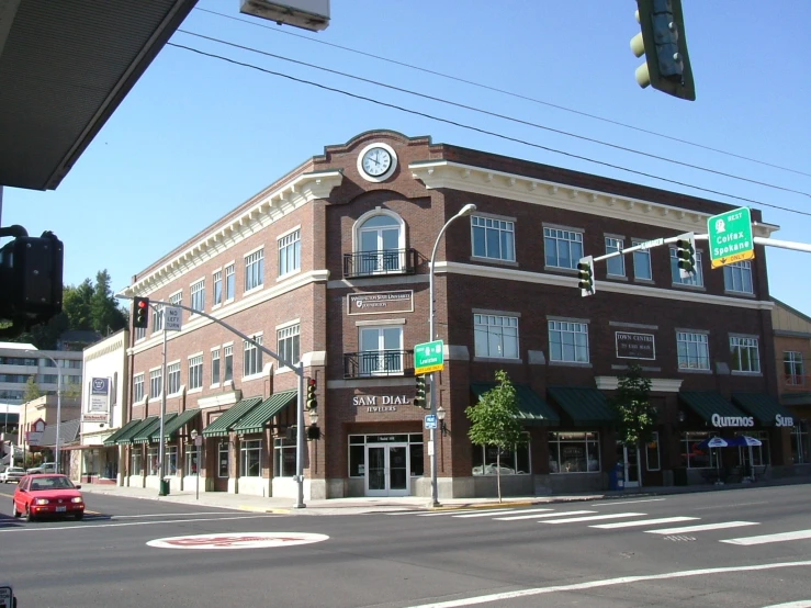 a large brick building is at the corner of the street