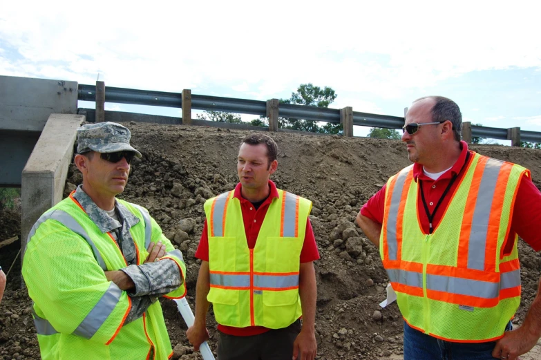 several men in safety vests are standing by the construction area