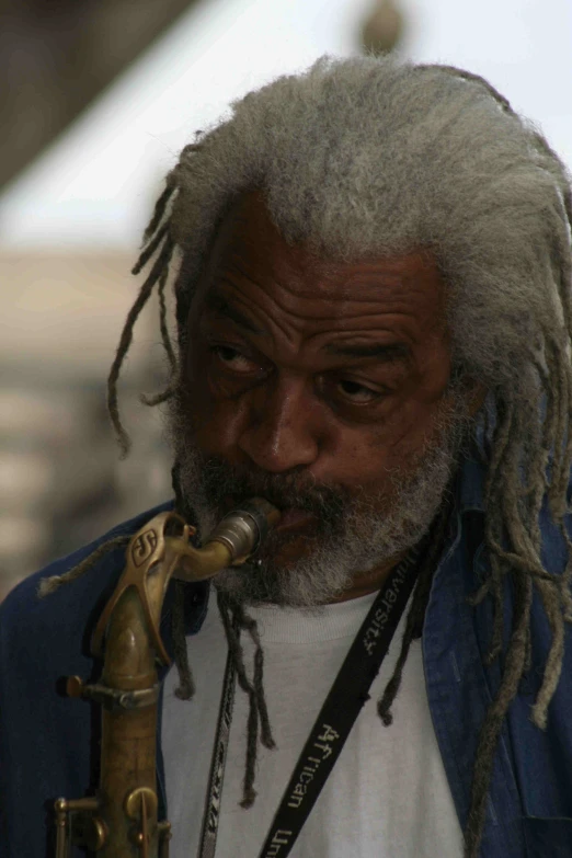 a man with white hair and dreadlocks playing a saxophone