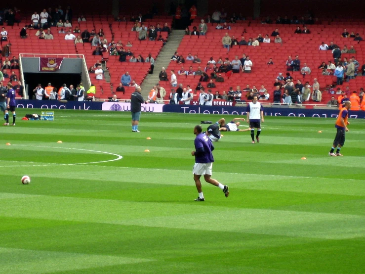 two teams playing soccer and spectators watch in the background