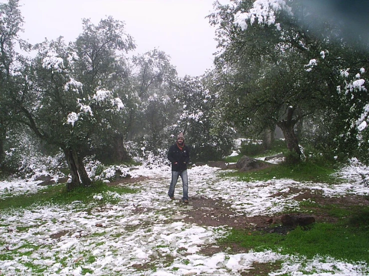 the person is standing in a snowy area with trees in the background