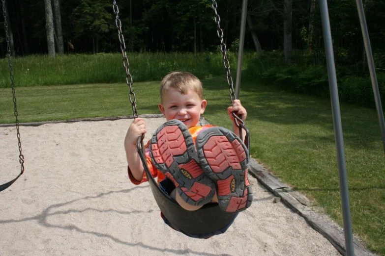 little boy playing in a tire swing