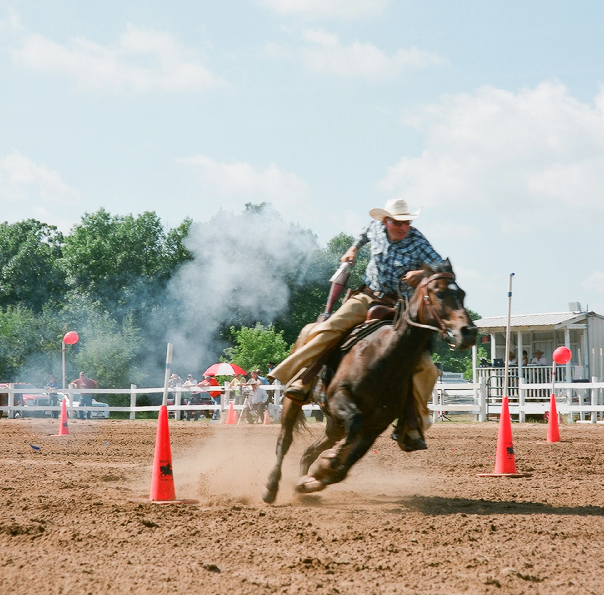 a man on a horse riding around some orange cones