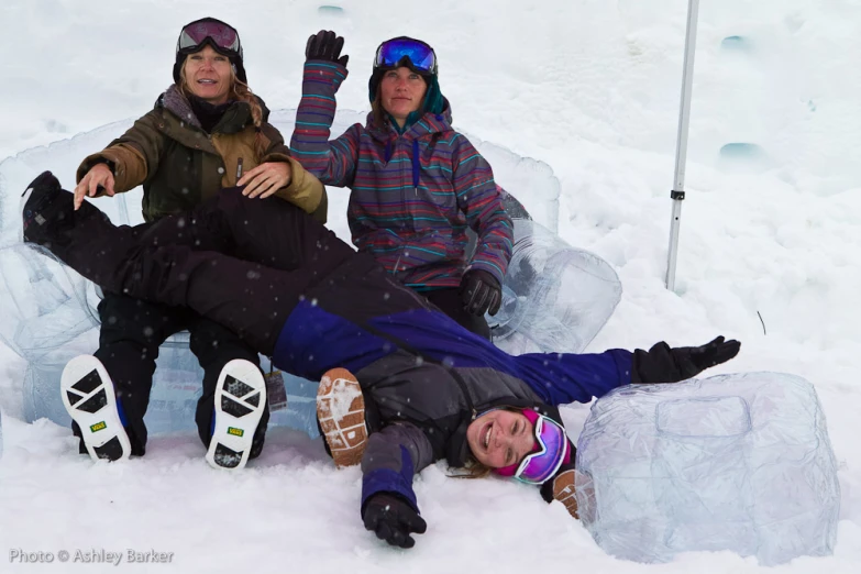 two snowboarders lying on their side in the snow