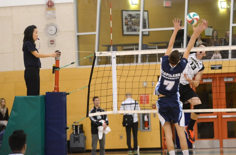 men playing volleyball in front of people sitting on the bleachers