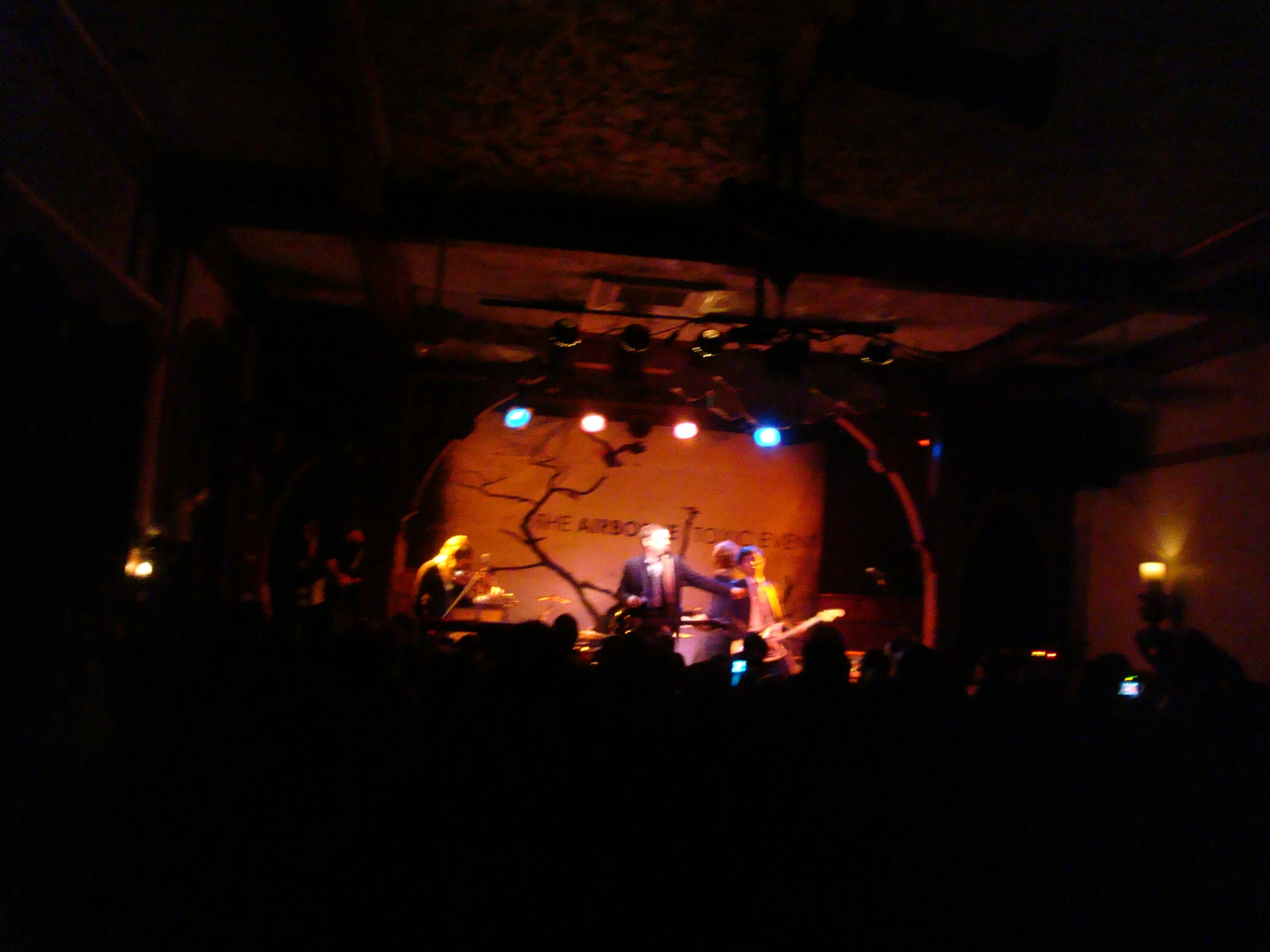 a band performing on stage at night in a darkened room