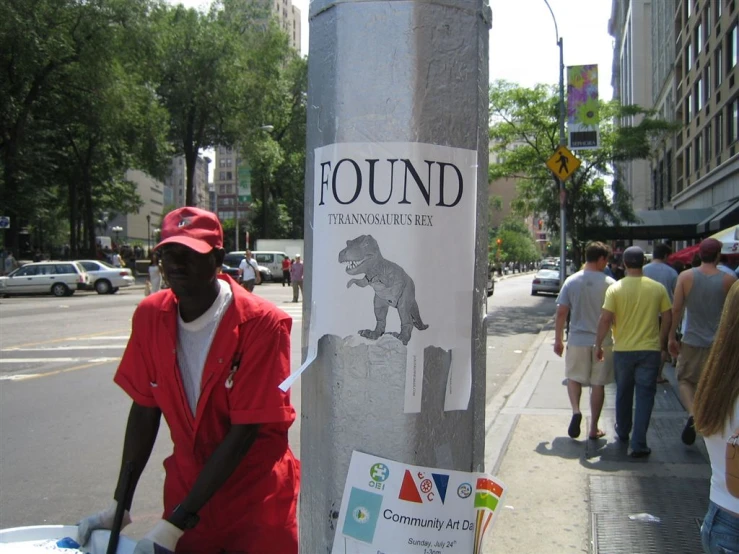 a man leaning against a telephone pole with a paper sign on it