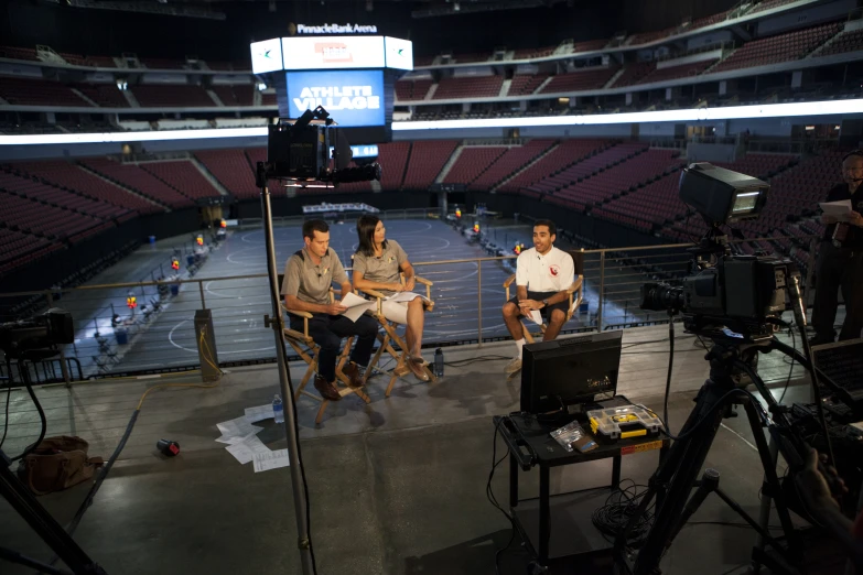 some people sit inside a stadium looking at a tv