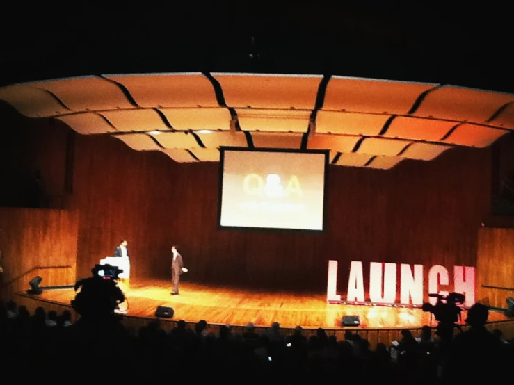 a person on a stage speaking with a man standing by