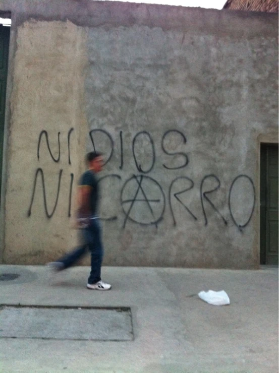 a man walking next to a graffiti covered wall