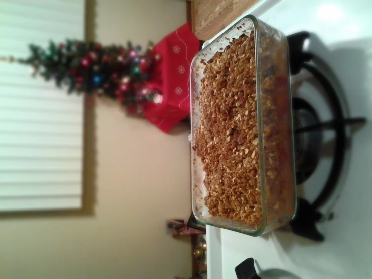 a glass dish with a food crumble in front of a christmas tree
