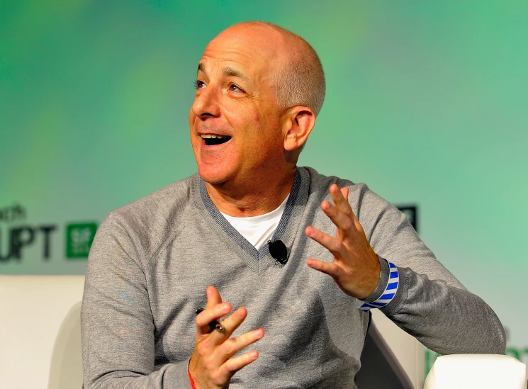 a bald man speaks while speaking in front of a screen