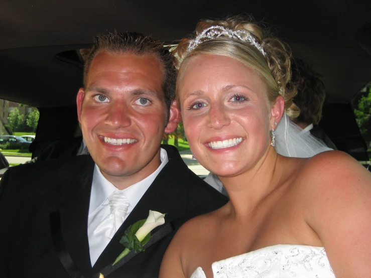 a man and woman in wedding attire in the back seat of a vehicle