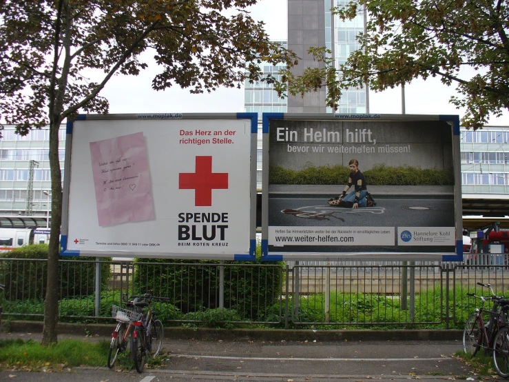 a billboard in front of a tall building with a red cross sign