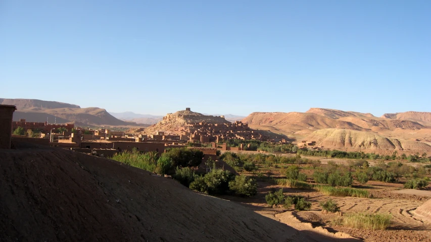 an area in the middle of a desert has many stone buildings and dirt hills